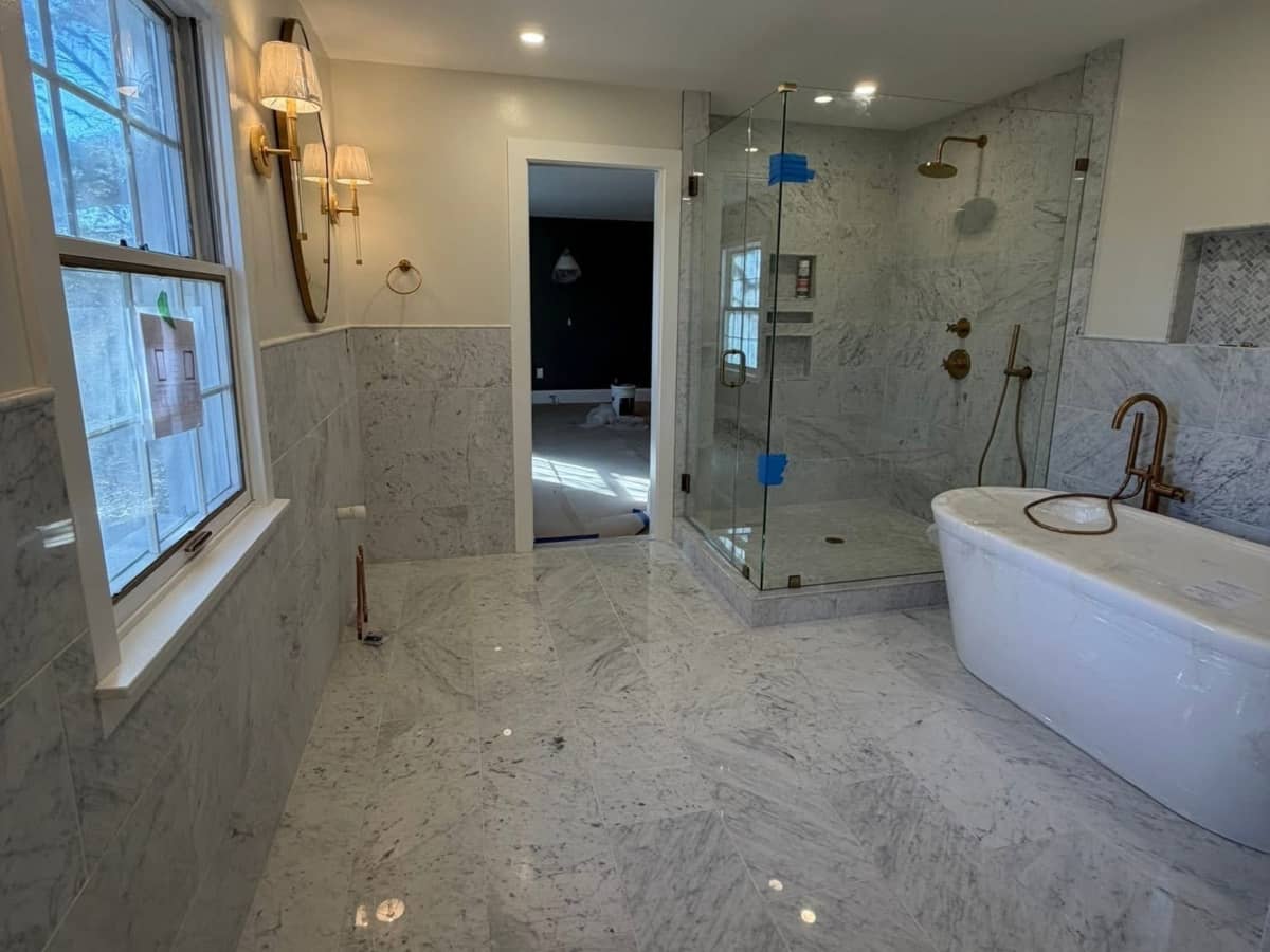 Master bathroom with marble tile, glass shower, and freestanding soaking tub