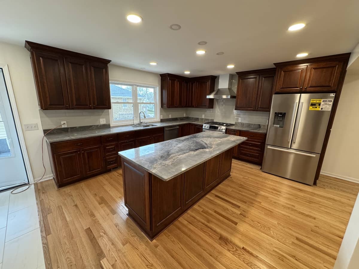 Luxurious kitchen remodel with dark wood cabinets, stone island, and hardwood flooring