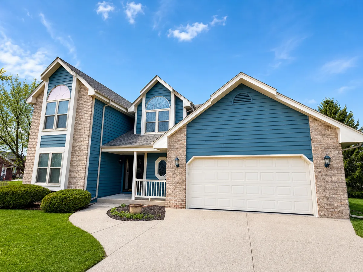 Blue home exterior with a white garage and brick accents
