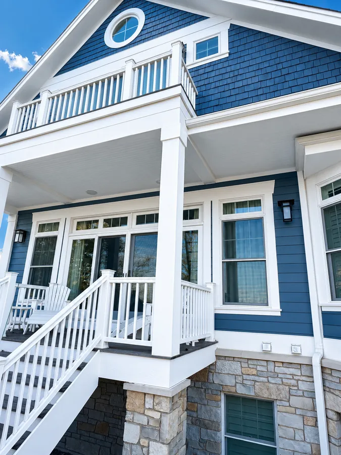Blue home exterior with white porch and stone base